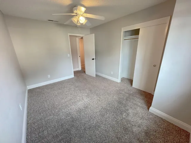 an empty room with a ceiling fan and a bathroom