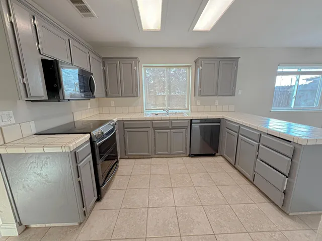 a kitchen with a sink a stove top oven and cabinetry