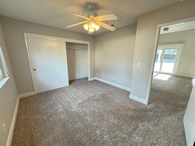 an empty room with closet and a chandelier fan