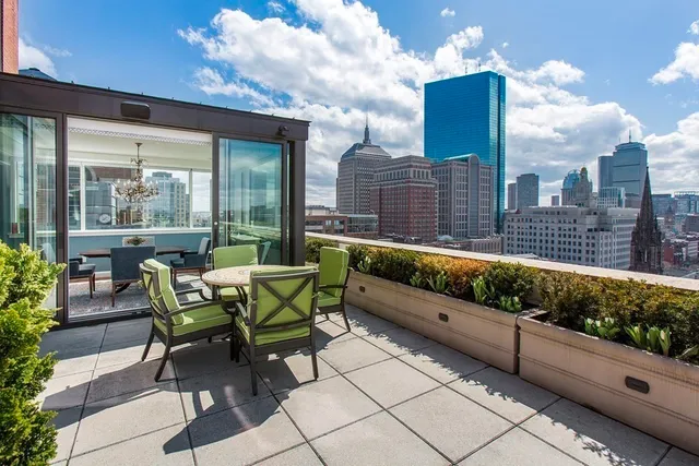 a roof deck with table and chairs and potted plants