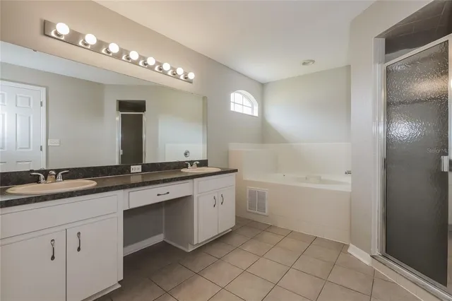 a bathroom with a granite countertop sink a large mirror and a bathtub