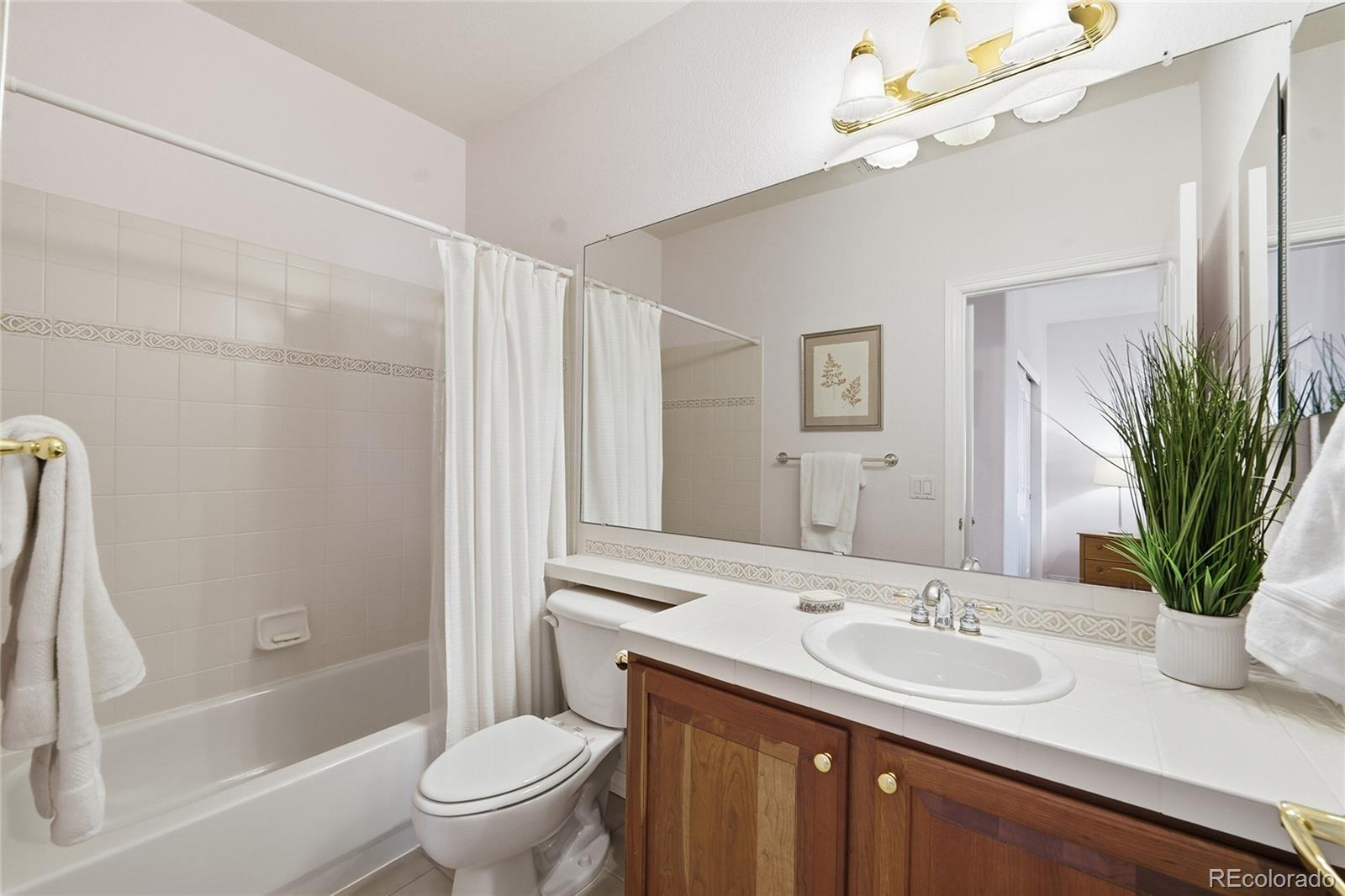 8967 Hunters Way Highlands Ranch, CO 80129 - Photo 33 of 50 a bathroom with a granite countertop sink a toilet and a mirror