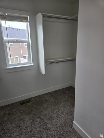 929 North 960 West Tremonton, UT 84337 - Photo 17 of 20 Bedroom space featuring a double-hung window, built-in closet organization with shelving and hanging rods, neutral wall paint, and gray textured carpeting