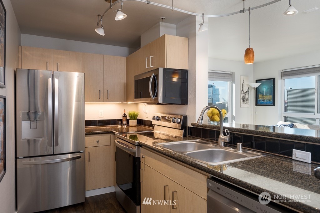 108 5th Avenue South, Unit 402 Seattle, WA 98104 - Photo 7 of 15 a kitchen that has a sink cabinets and stainless steel appliances