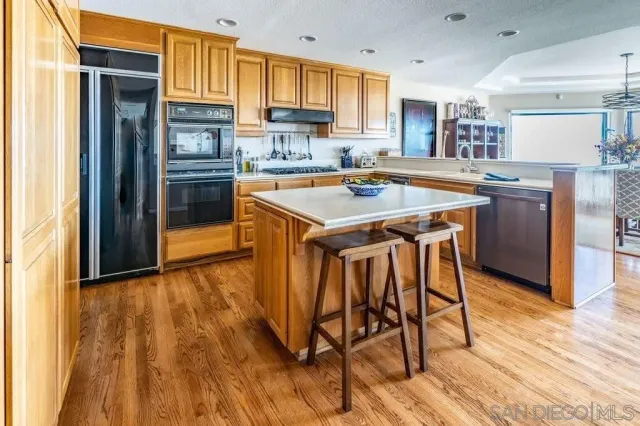 a kitchen with a sink a stove and chairs with wooden floor