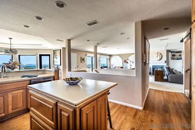 a kitchen with stainless steel appliances granite countertop a kitchen island a stove a sink a dining table and chairs with wooden floor