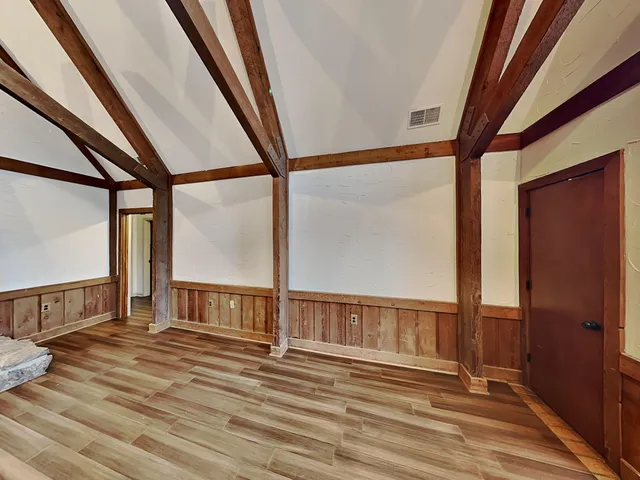 a view of an empty room with wooden floor and windows