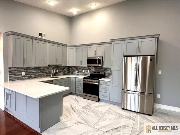 a kitchen with stainless steel appliances granite countertop a refrigerator a stove and a sink