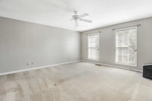 an empty room with a ceiling fan and windows