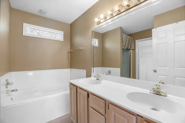 a bathroom with a tub a sink and a mirror