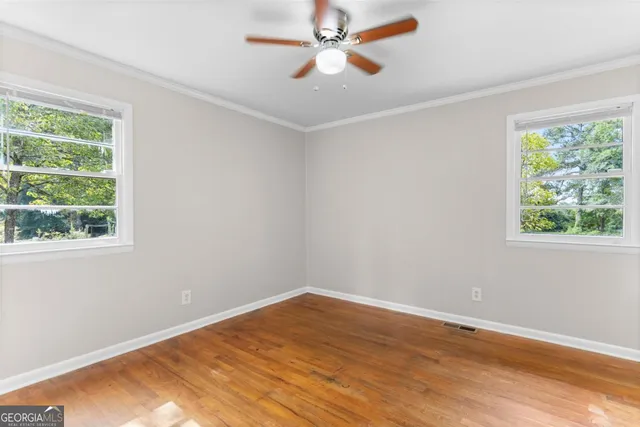 a view of empty room with wooden floor and fan