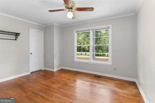 a view of empty room with wooden floor and fan