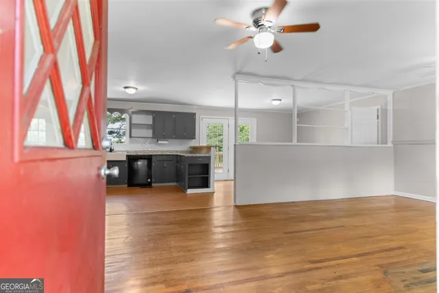 a view of a kitchen with kitchen island a sink wooden floor and a stove top oven