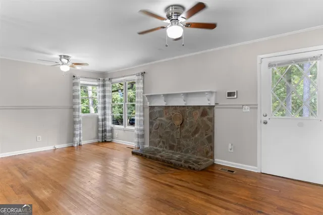 a view of empty room with wooden floor and fan