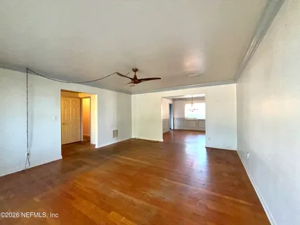a view of empty room with wooden floor and fan