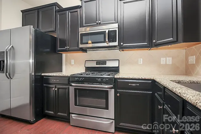 a kitchen with granite countertop a stove and a microwave