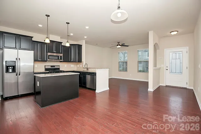 a kitchen with stainless steel appliances granite countertop a refrigerator a stove top oven a sink dishwasher and a refrigerator with wooden floor