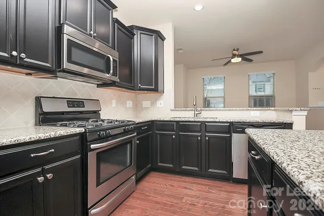a kitchen with stainless steel appliances granite countertop a stove microwave and sink