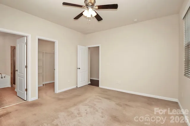 a view of an empty room and chandelier fan