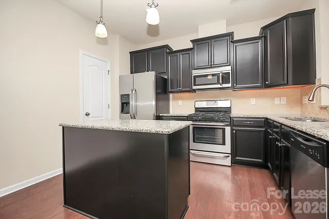 a kitchen with stainless steel appliances granite countertop a refrigerator stove and sink