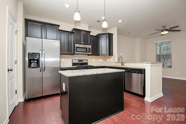 a kitchen with kitchen island granite countertop a sink cabinets and stainless steel appliances
