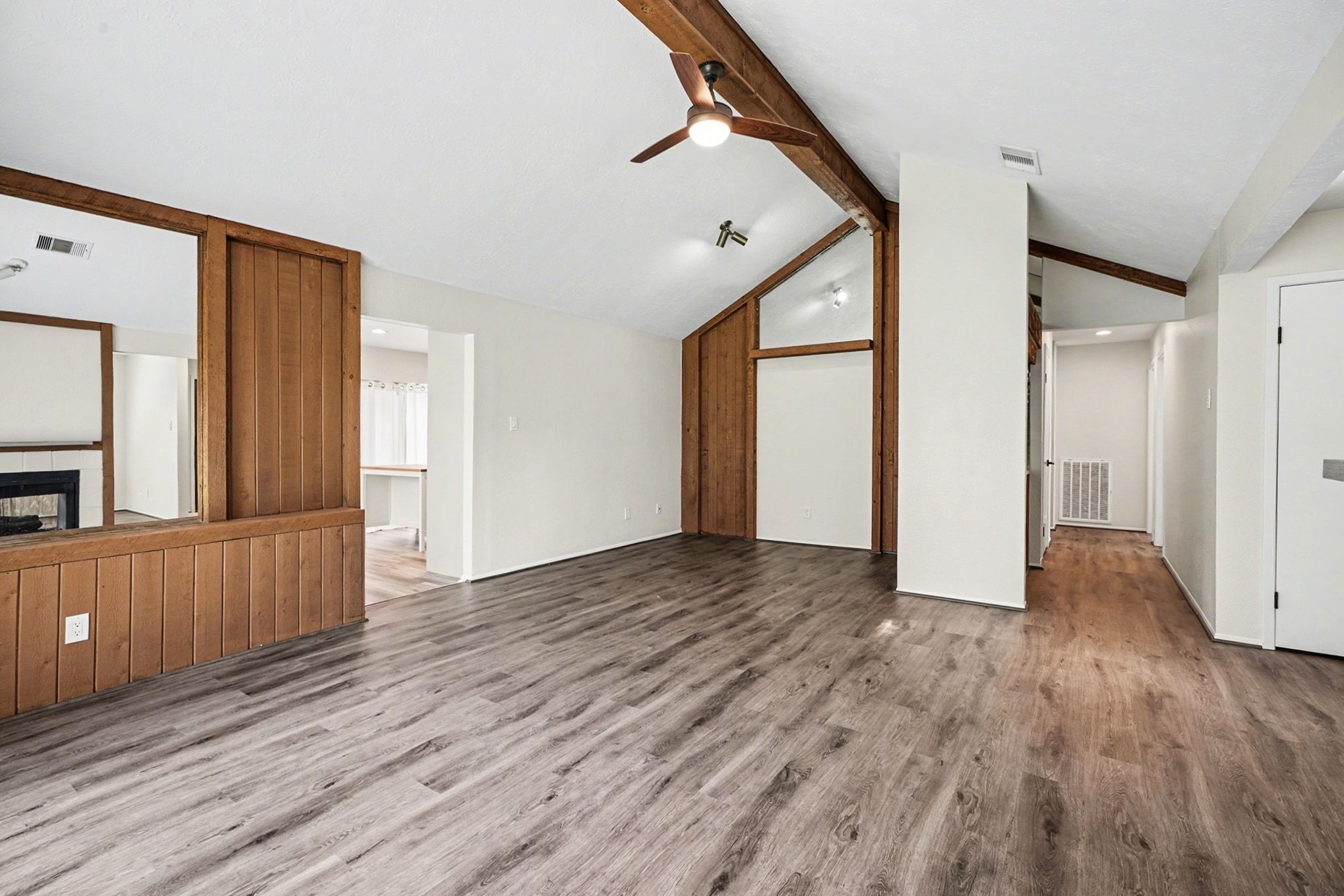 1723 Linfield Way Houston, TX 77058 - Photo 9 of 21 Spacious living area with vaulted ceilings, wood accents, and modern flooring. Features an open layout with ample natural light and a visible fireplace, creating a cozy yet contemporary ambiance.