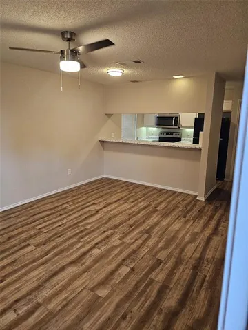 a view of kitchen and empty room with wooden floor