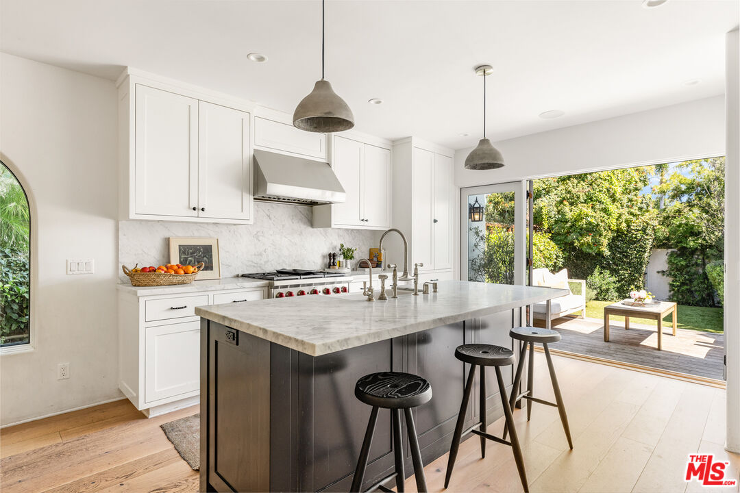 a kitchen with stainless steel appliances granite countertop a stove a refrigerator a sink a dining table and chairs with wooden floor