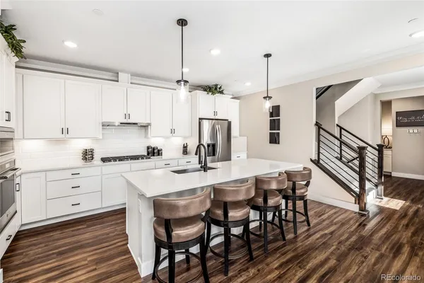 a kitchen with stainless steel appliances kitchen island granite countertop a table chairs and white cabinets