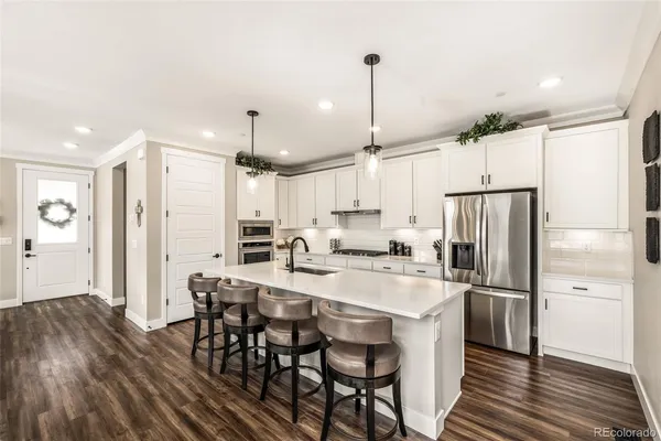 a kitchen with refrigerator a sink and chairs