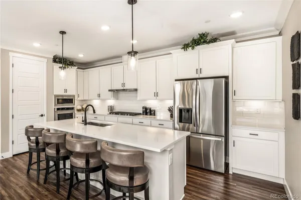 a kitchen with stainless steel appliances granite countertop a refrigerator a sink a stove a dining table and chairs