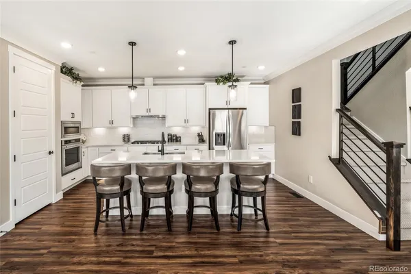 a dining room with stainless steel appliances kitchen island granite countertop a table chairs and a refrigerator
