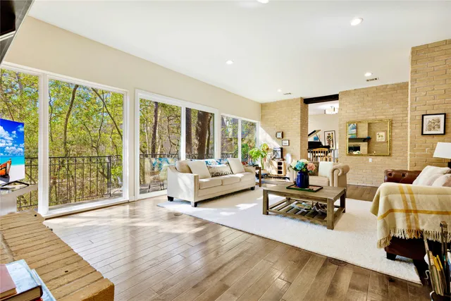 a living room with furniture large windows and wooden floor