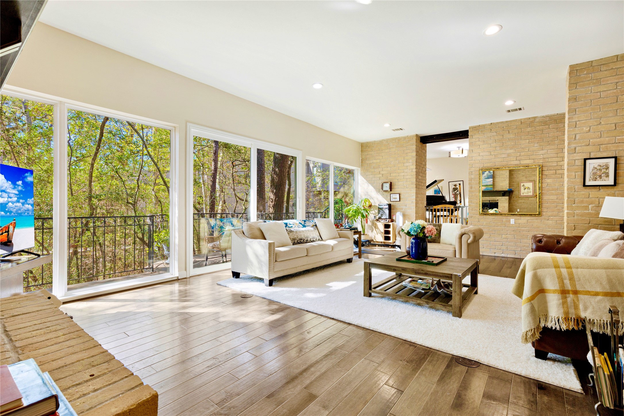 a living room with furniture large windows and wooden floor