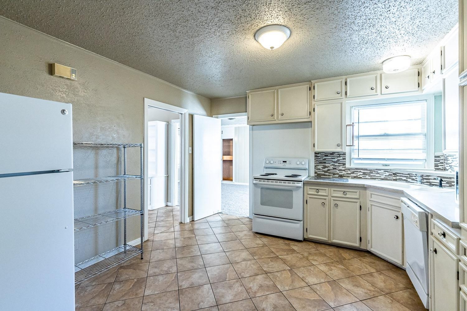 3708 27th Street Lubbock, TX 79410 - Photo 9 of 23 a kitchen with a stove a sink and a refrigerator