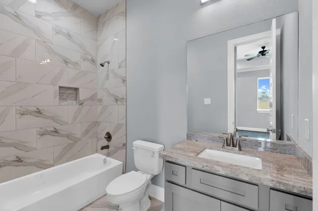 a bathroom with a granite countertop sink a toilet and bathtub
