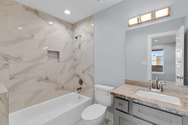 a bathroom with a granite countertop sink toilet a large mirror a bathtub and shower