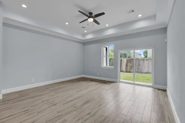 an empty room with wooden floor and a ceiling fan