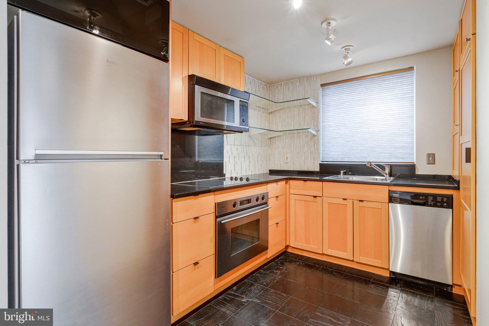 510 N Street Southwest, Unit N622 Washington, DC 20024 - Photo 9 of 29 a kitchen with stainless steel appliances granite countertop a refrigerator a microwave oven a sink and white cabinets with wooden floor