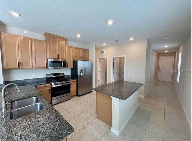 a kitchen with stainless steel appliances granite countertop a refrigerator and a sink