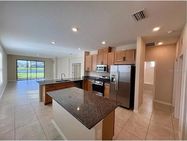 a kitchen with stainless steel appliances granite countertop a refrigerator a sink a stove a microwave and island
