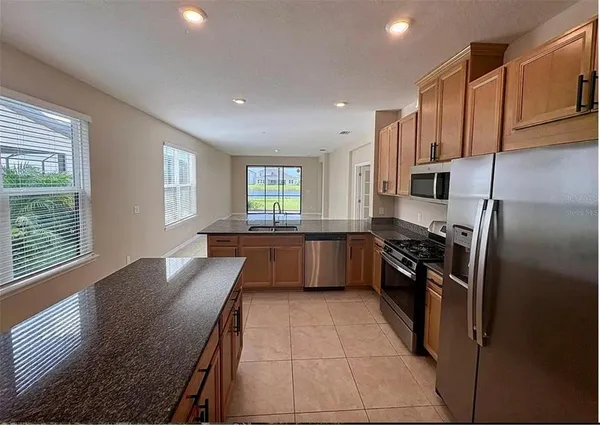 a kitchen with granite countertop a refrigerator stove top oven and sink
