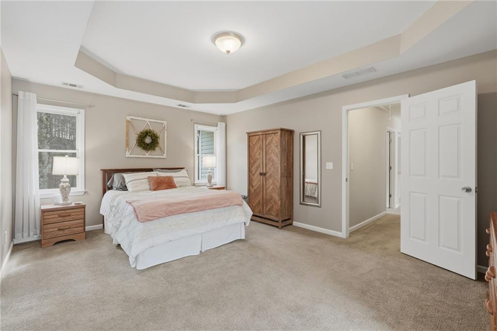 60 Gilbert Circle Northeast Suwanee, GA 30024 - Photo 16 of 47 a spacious bedroom with a bed and painting on the wall