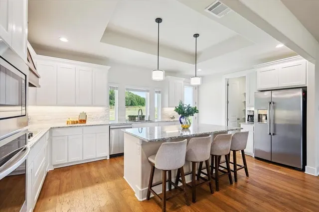 a kitchen with stainless steel appliances kitchen island granite countertop a dining table chairs and white cabinets