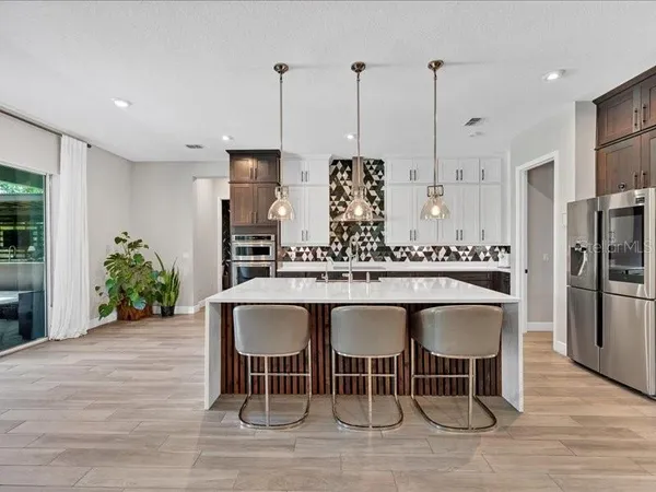 a dining table chairs with a wooden floor and kitchen view