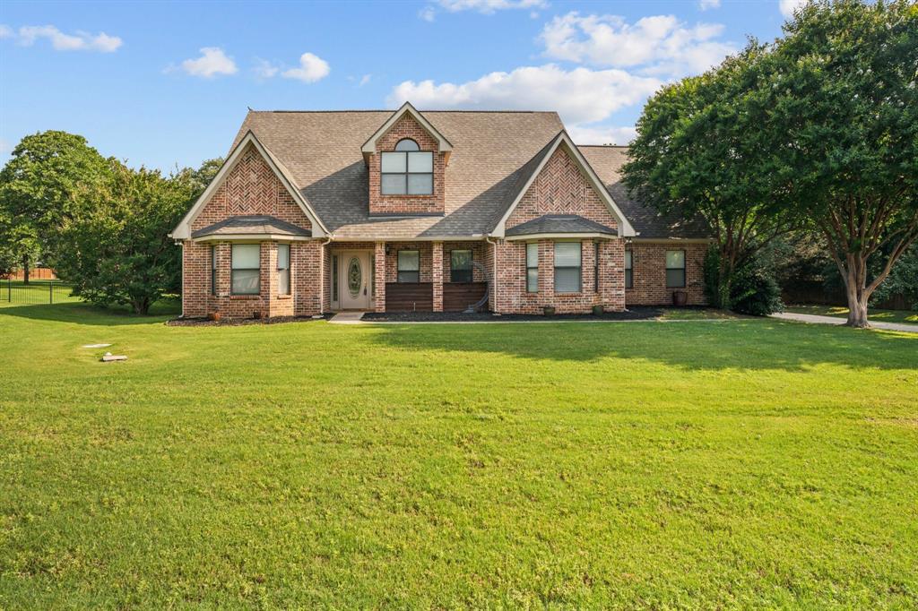 View of front of property with a shingled roof, a front lawn, and brick siding