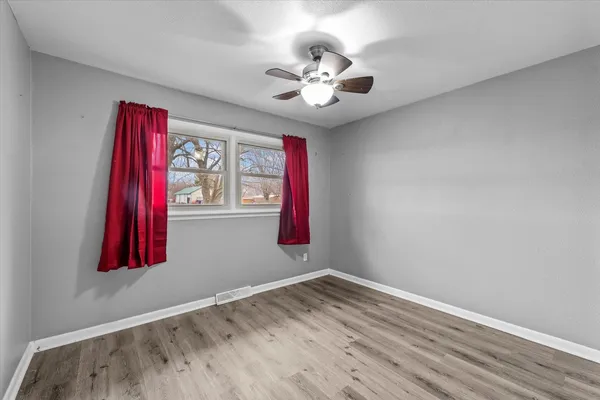 a view of a bedroom with wooden floor and fan