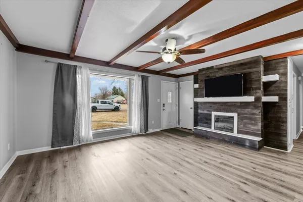 a view of an empty room with wooden floor fireplace and a window