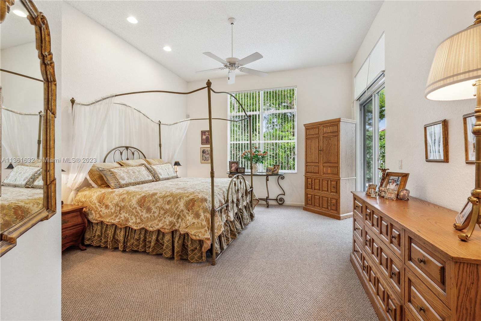 6666 Northwest 23rd Terrace Boca Raton, FL 33496 - Photo 4 of 38 a spacious bedroom with a bed a couch and a dresser next to a window