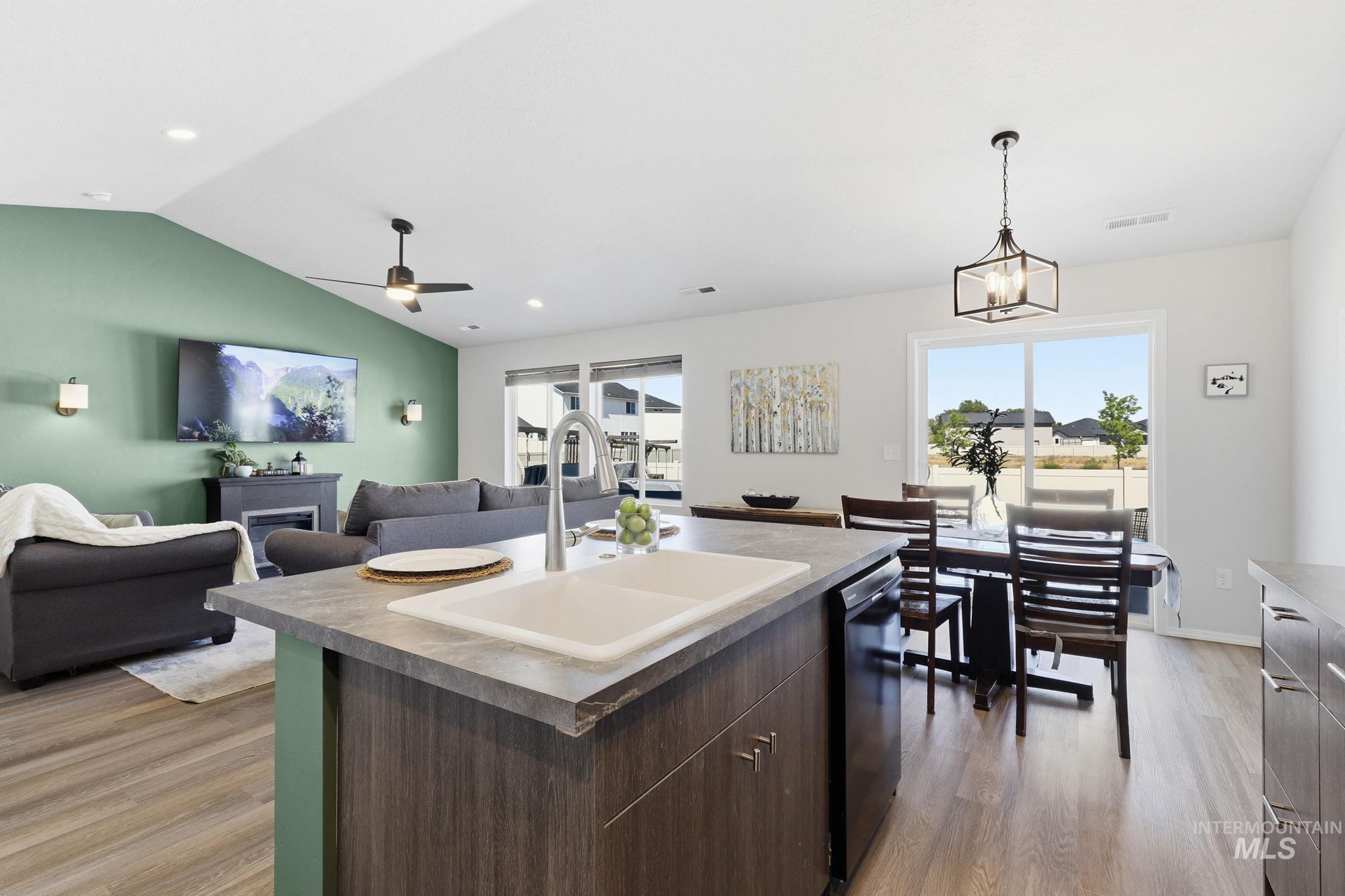 16780 Breton Way Caldwell, ID 83607 - Photo 15 of 28 Contemporary kitchen featuring wood-finish cabinetry with brushed nickel hardware, solid surface countertops, a white subway tile backsplash, a black electric range with an overhead microwave, and wood-finish flooring
